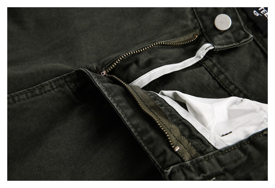 Close-up of charcoal trousers with the fly unzipped, revealing a white inner layer and metal button.