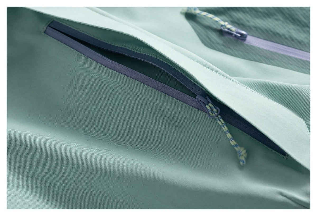 Close-up of a concealed lavender zipper pocket on pale mint jacket fabric.