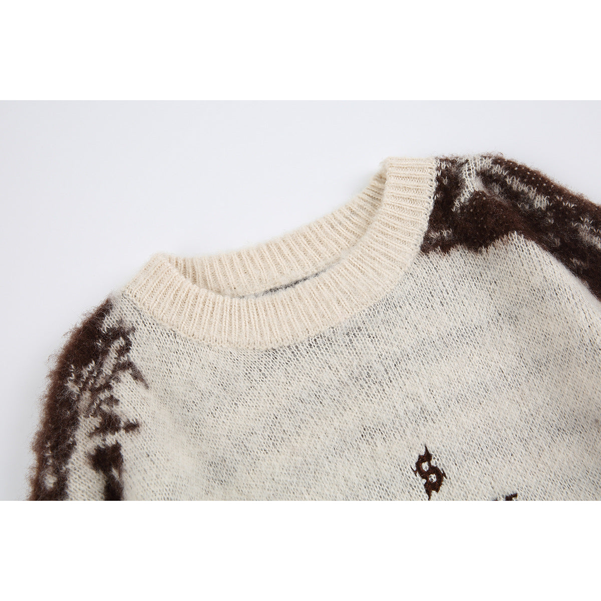 Close-up of an ivory sweater's ribbed crew neck and dark brown patterned shoulders.