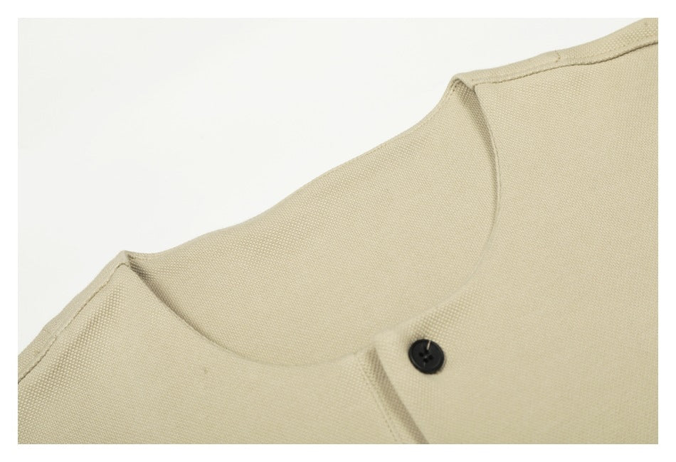 Close-up of the cream top's neckline and single black button on the short placket.