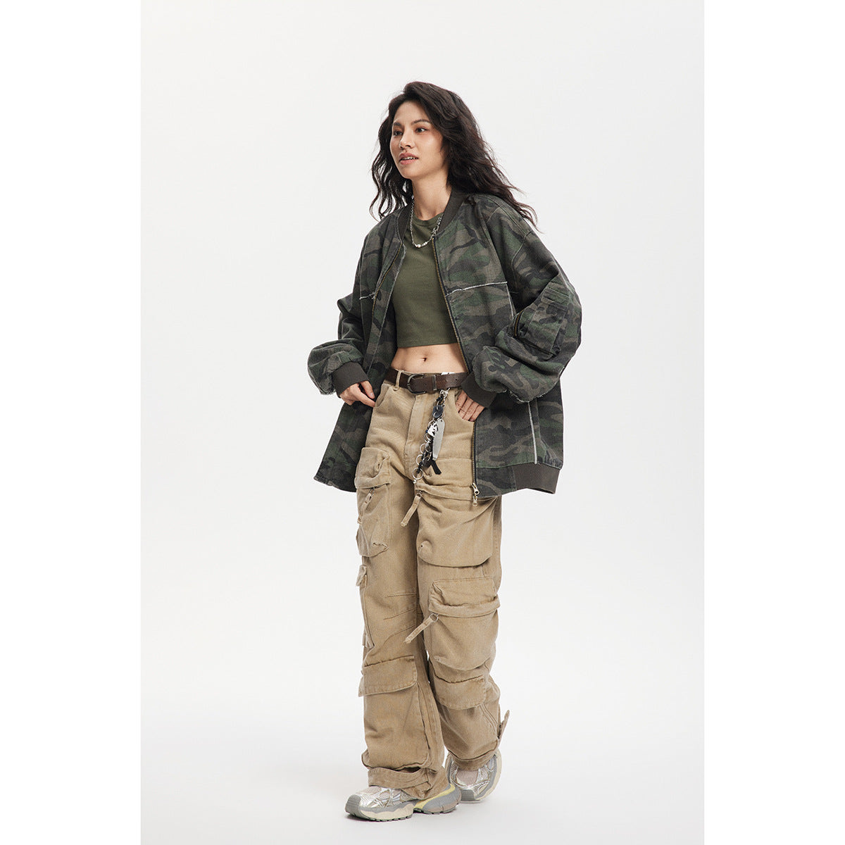 Model wearing an oversized dark green camouflage bomber jacket open over a crop top, with ribbed trim and a sleeve pocket.