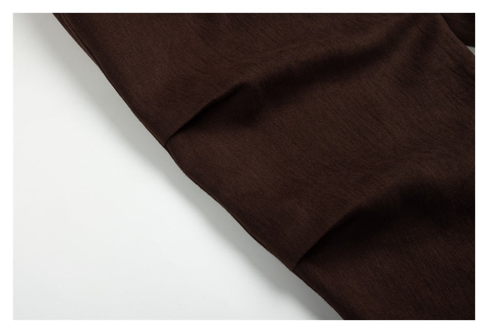 Close-up of dark brown fabric draped in soft folds, showing a stitched seam.