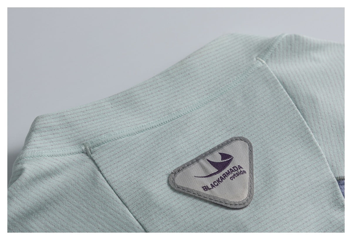 Close-up of a triangular BLACK ARMADA patch on pale mint-gray striped fabric.