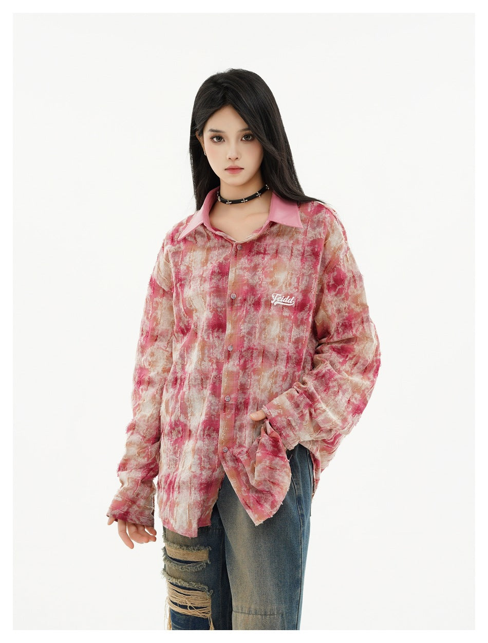 Model wearing an oversized pink and beige abstract-print button-up shirt with a pink collar and chest lettering.