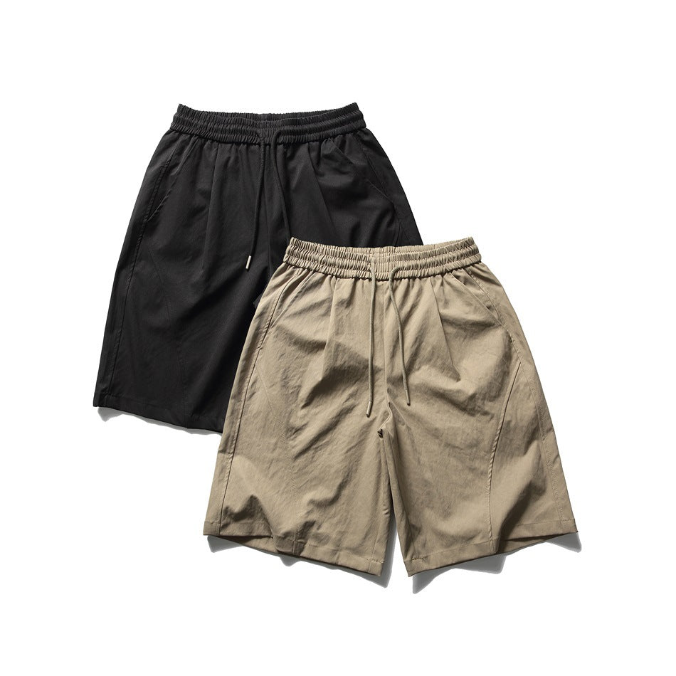 Front views of relaxed shorts in black and beige, with elastic waistbands, drawstrings, and side pockets.