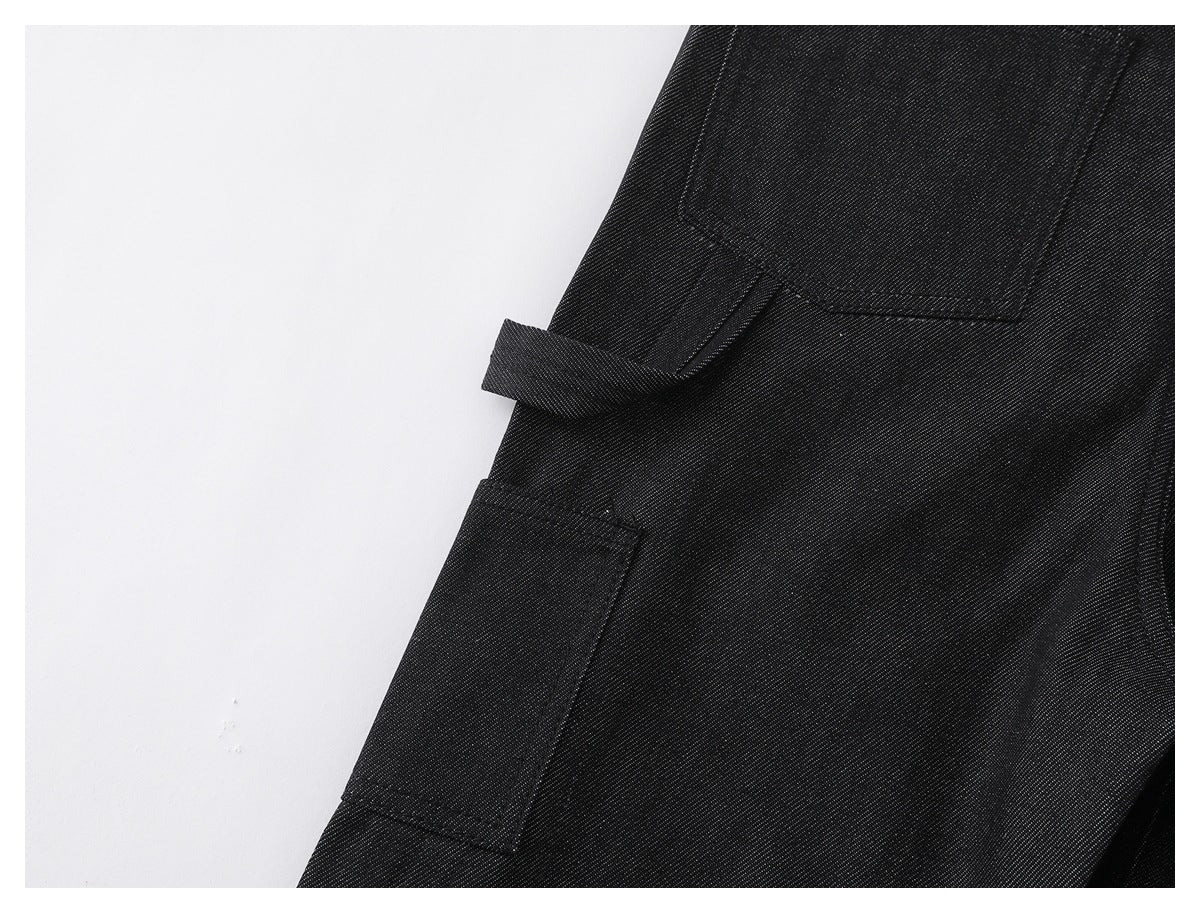 Close-up of black pants showing a side pocket, a small fabric loop, and stitching.
