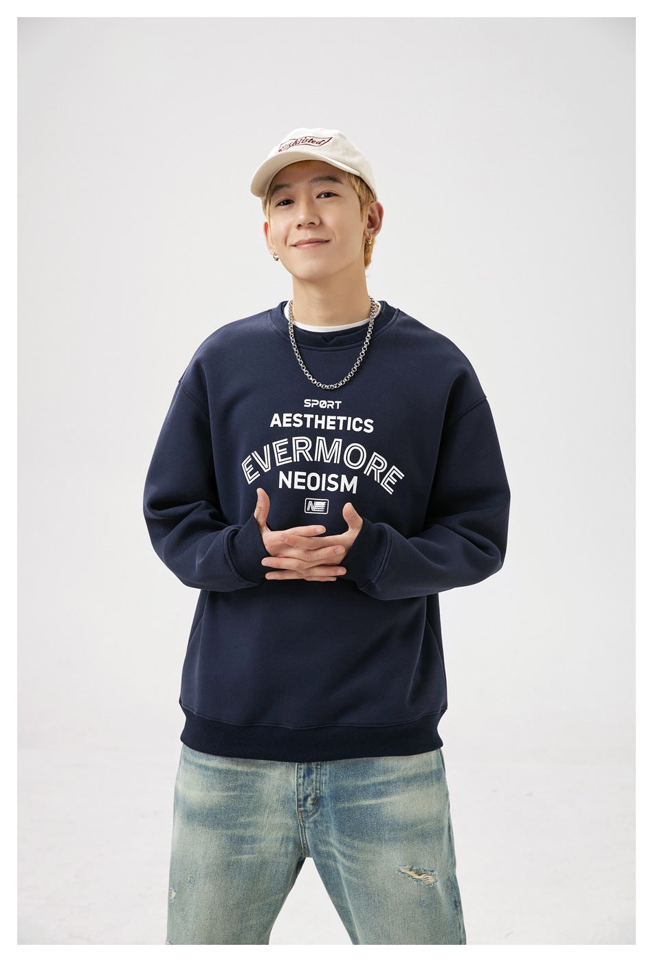Closer view of a model wearing a navy sweatshirt with white front lettering and ribbed cuffs and hem.