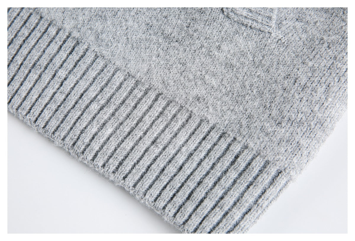 Close-up of a light gray knit garment with a dark gray ribbed edge.