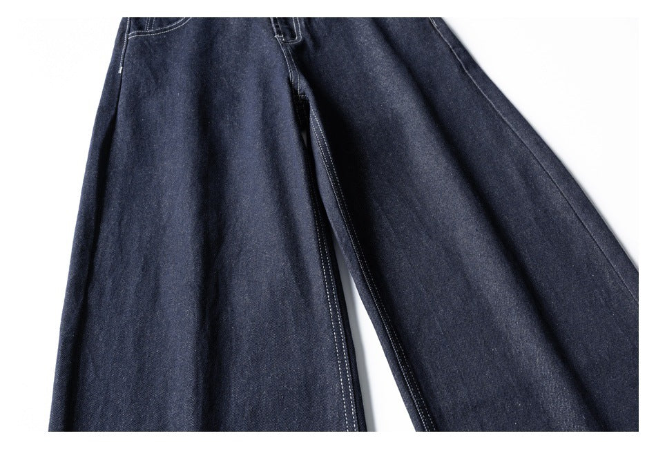 Close-up of dark indigo jeans showing the wide legs and contrast-stitched inseam.