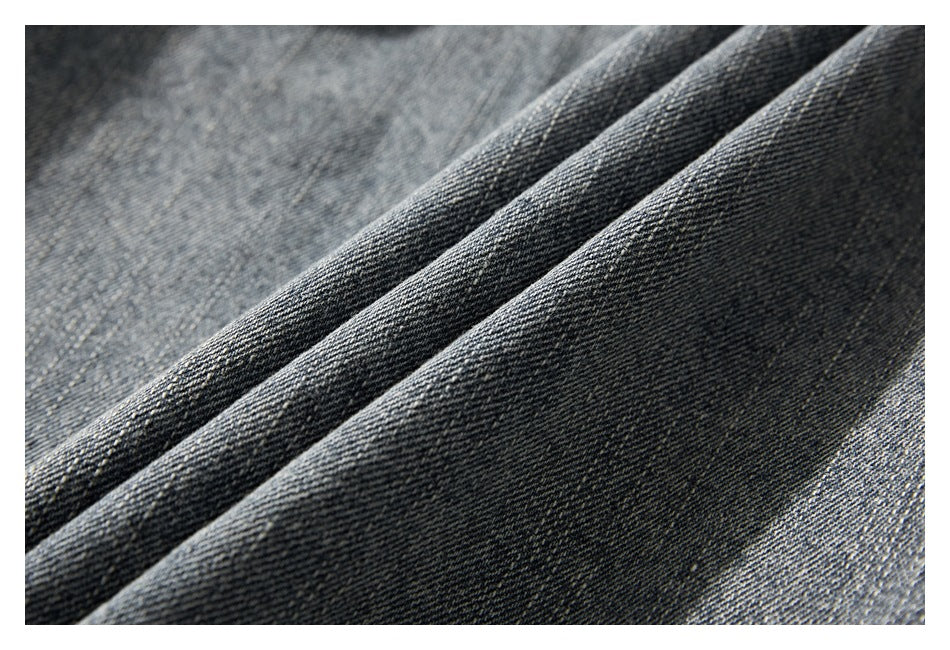 Macro view of the denim jacket's dark, faded blue-gray woven fabric and folds.