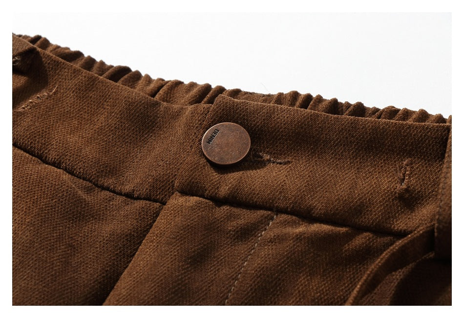 Close-up of the brown trousers' gathered waistband and button, with small lettering on the button.
