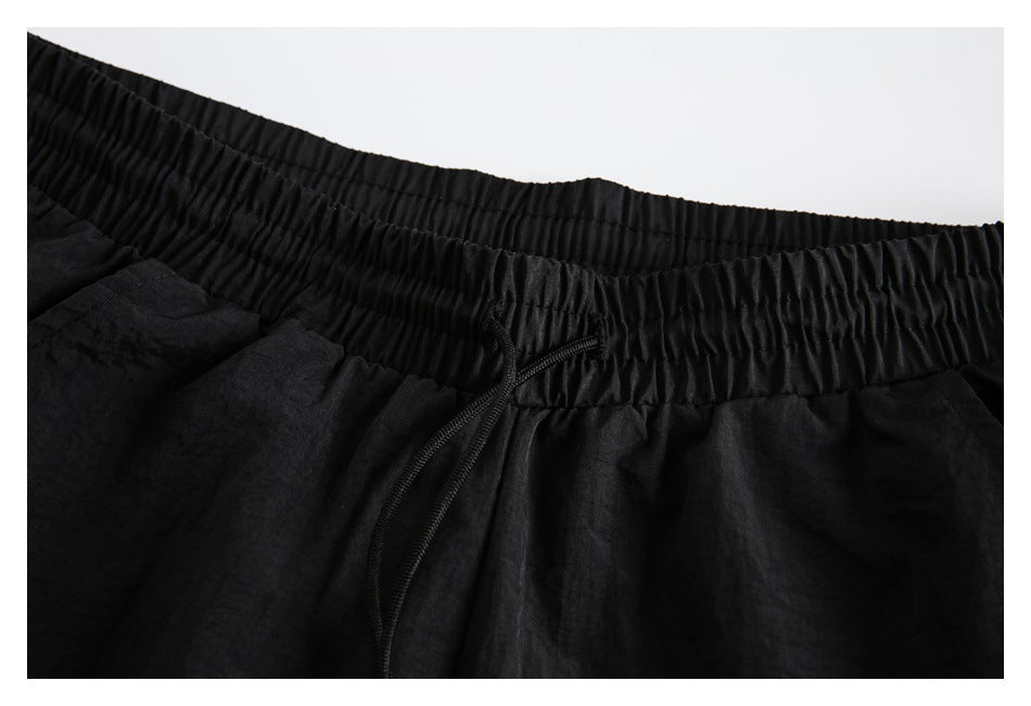 Close-up of the black pants' gathered elastic waistband and black drawstring.