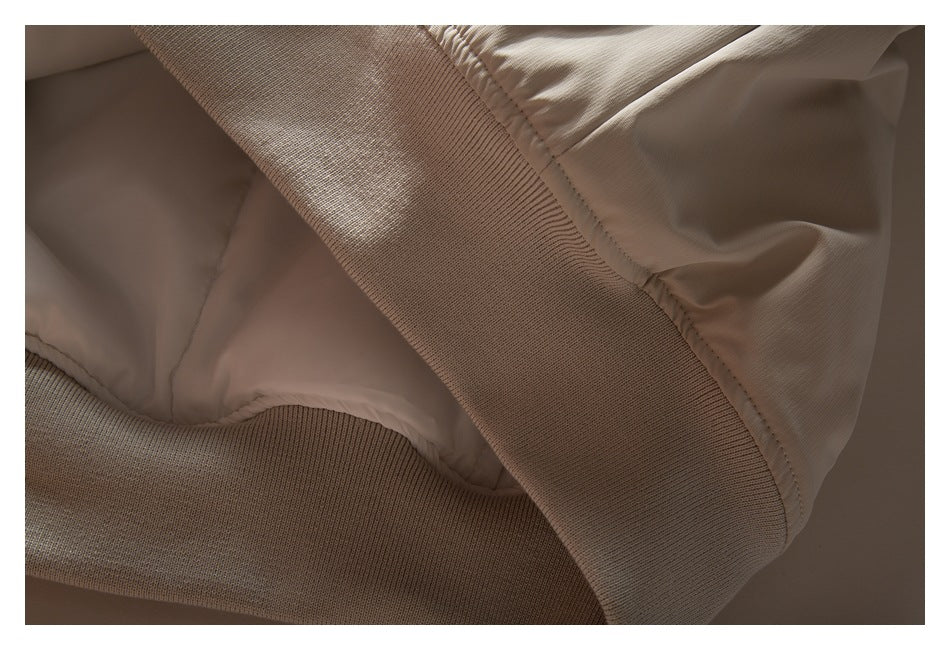 Close-up of the beige jacket's ribbed hem and smooth inner lining.
