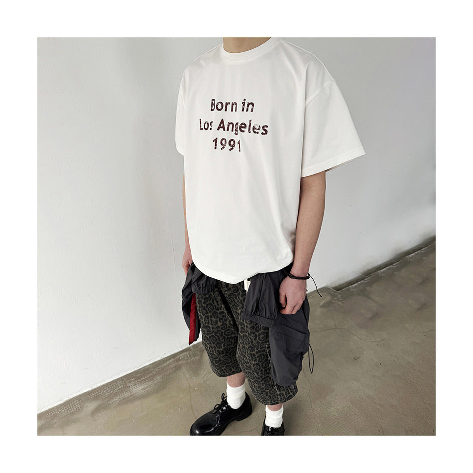 Model wearing off-white 'Born in Los Angeles 1991' T-shirt with leopard-print shorts and black shoes, cropped at face