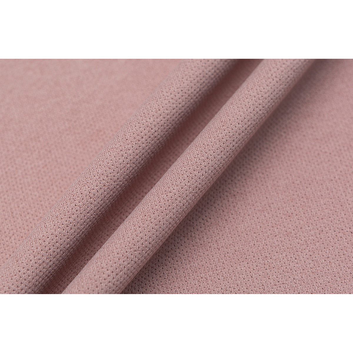 Close-up of dusty pink fabric showing its small perforated texture and soft folds.