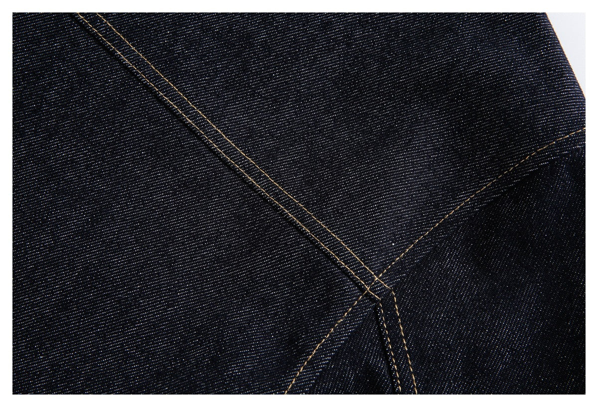 Close-up of intersecting seams and tan topstitching on dark indigo denim.