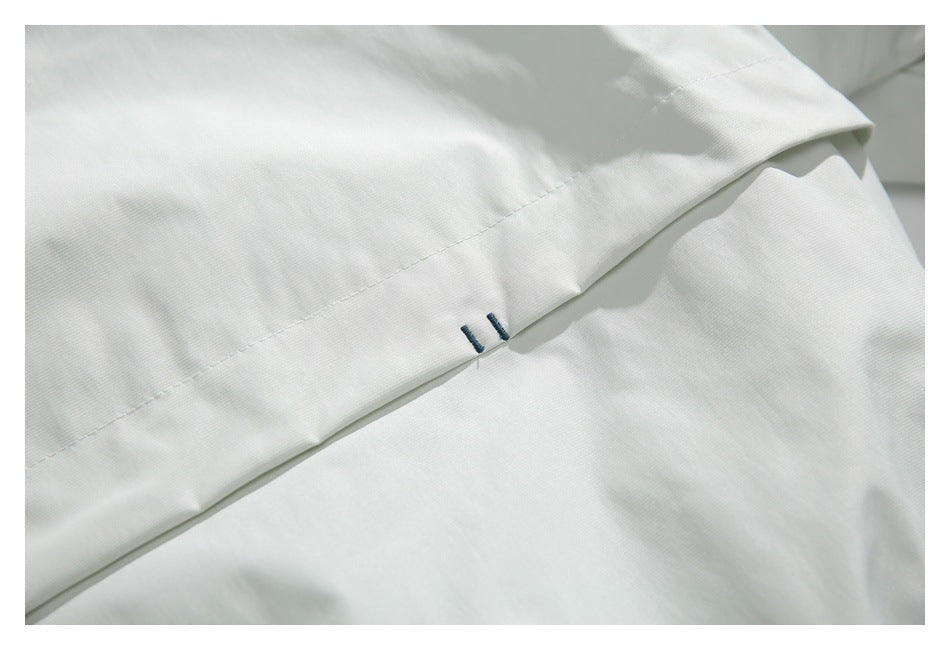 Close-up of a white jacket seam with two small dark stitch marks.