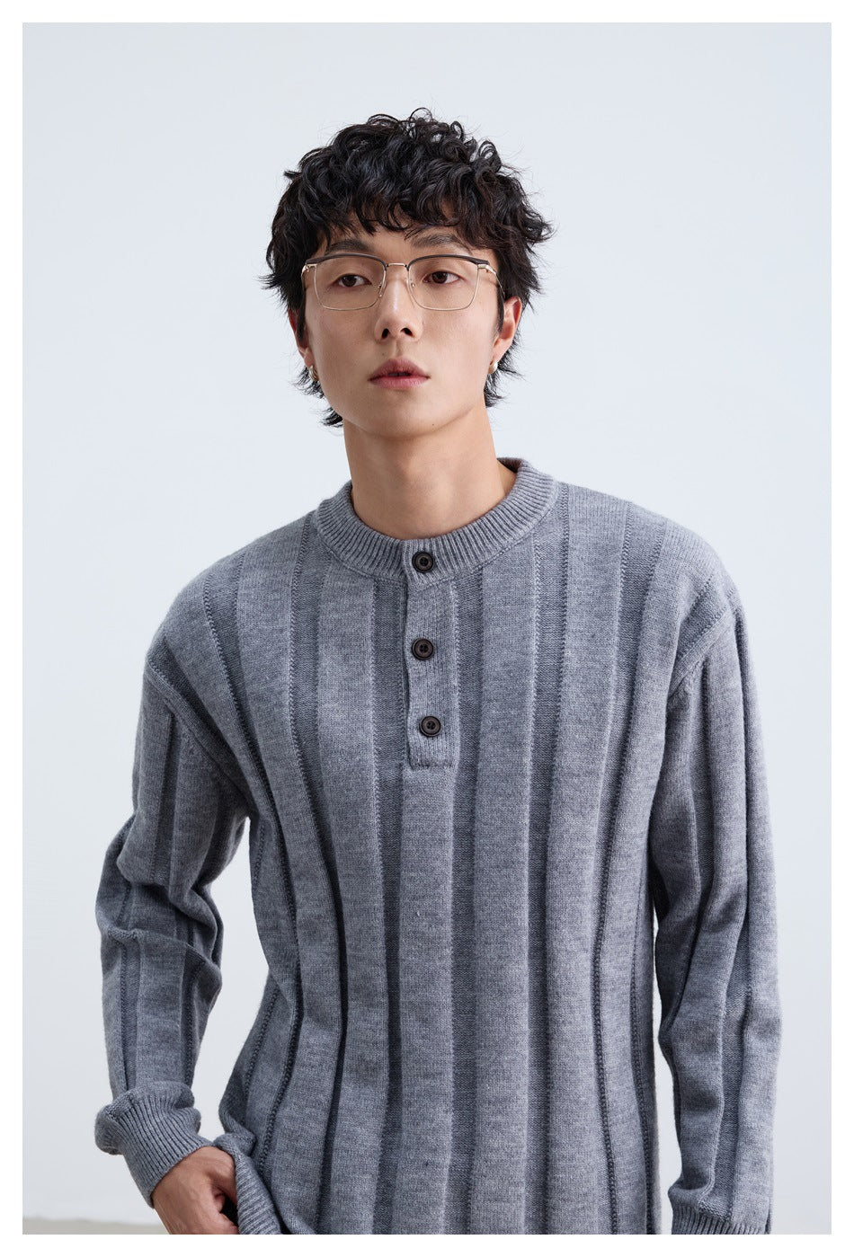 Close view of the gray sweater's vertical panels, ribbed collar, and three-button placket on a model.
