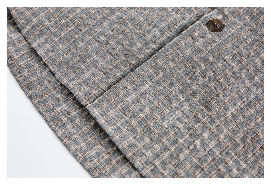 Close-up of gray-brown plaid shirt fabric with a dark button and overlapping front placket.
