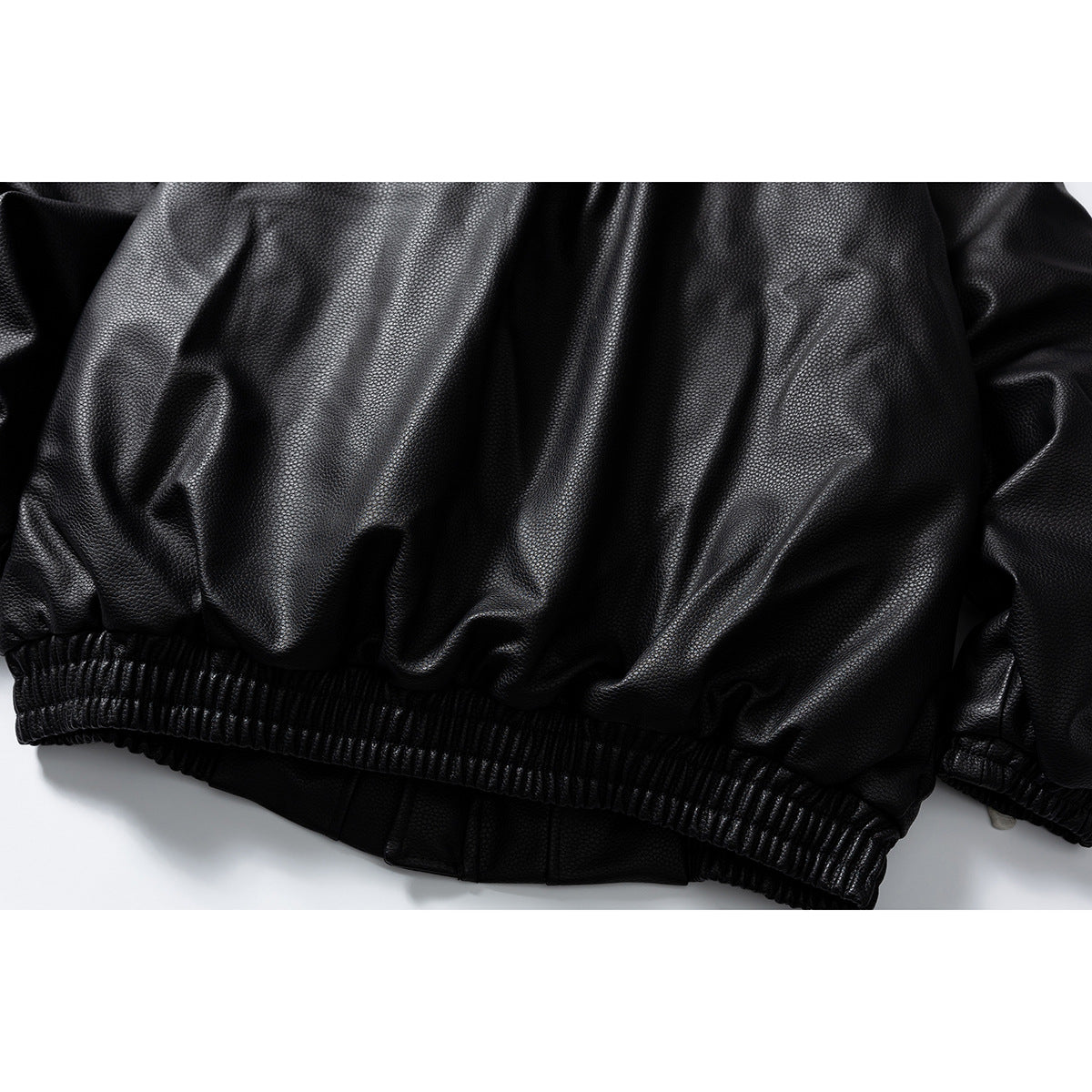 Close-up of the black jacket's gathered elastic hem and textured surface.