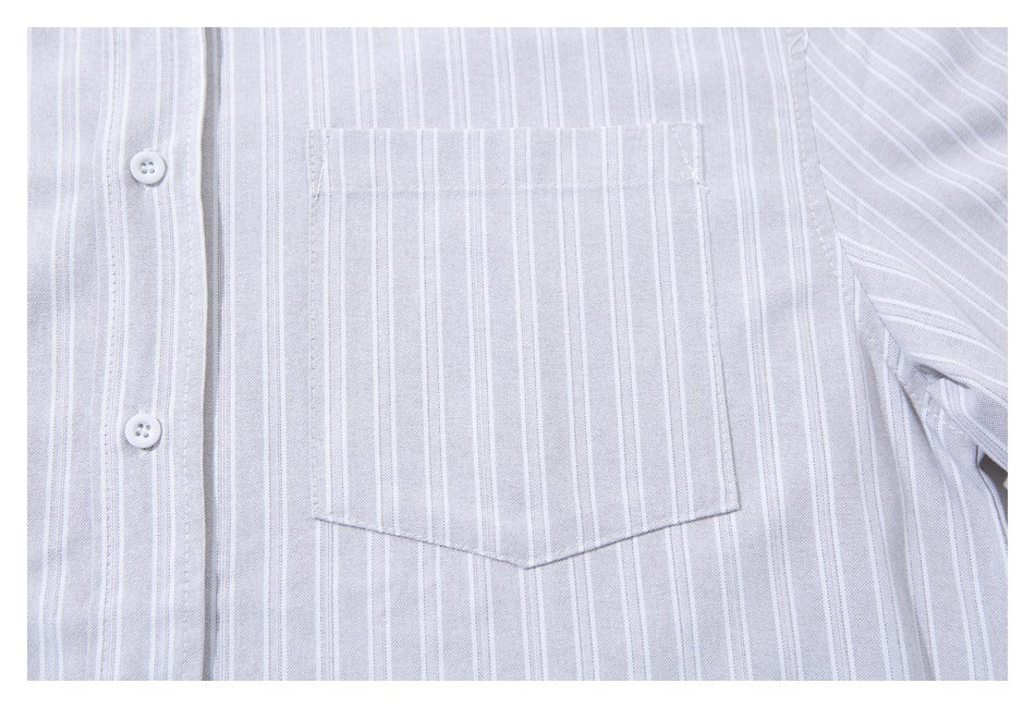 Close-up of a pale gray shirt with thin white vertical stripes, two white buttons, and a pointed chest pocket.