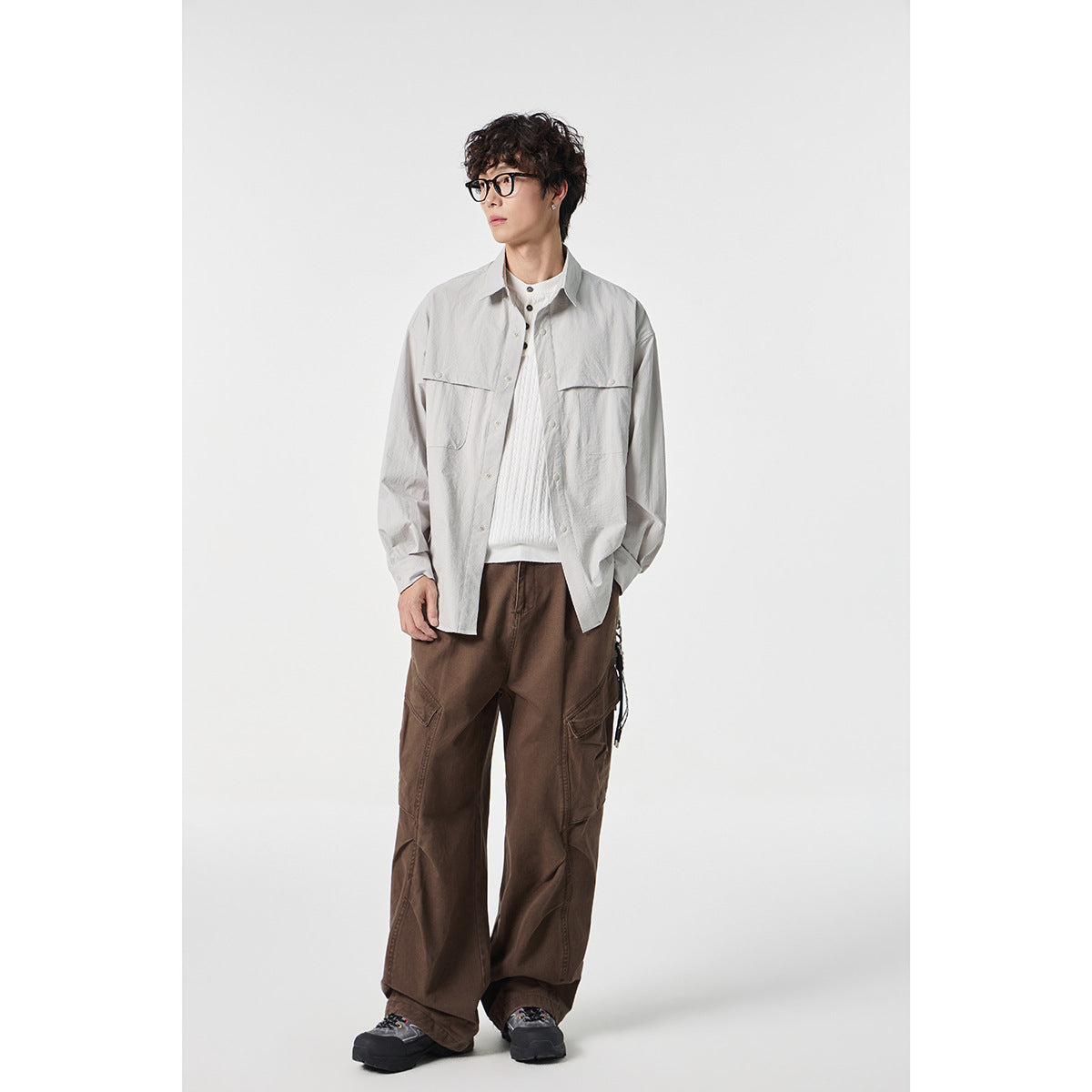 Model wearing a light gray oversized button-up shirt with flap chest pockets and brown cargo pants.