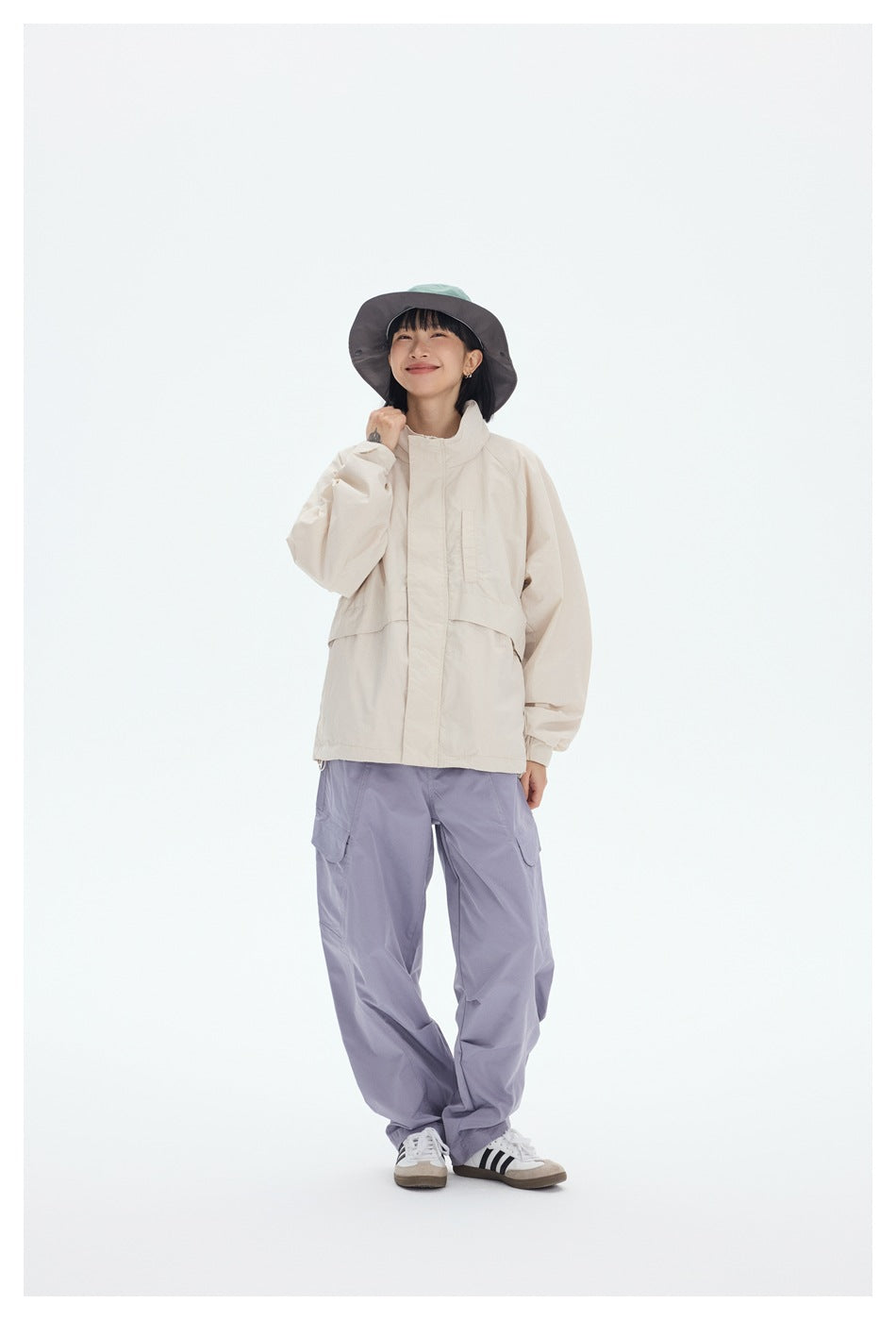 Person wearing an off-white stand-collar jacket with lavender cargo pants, a bucket hat and sneakers