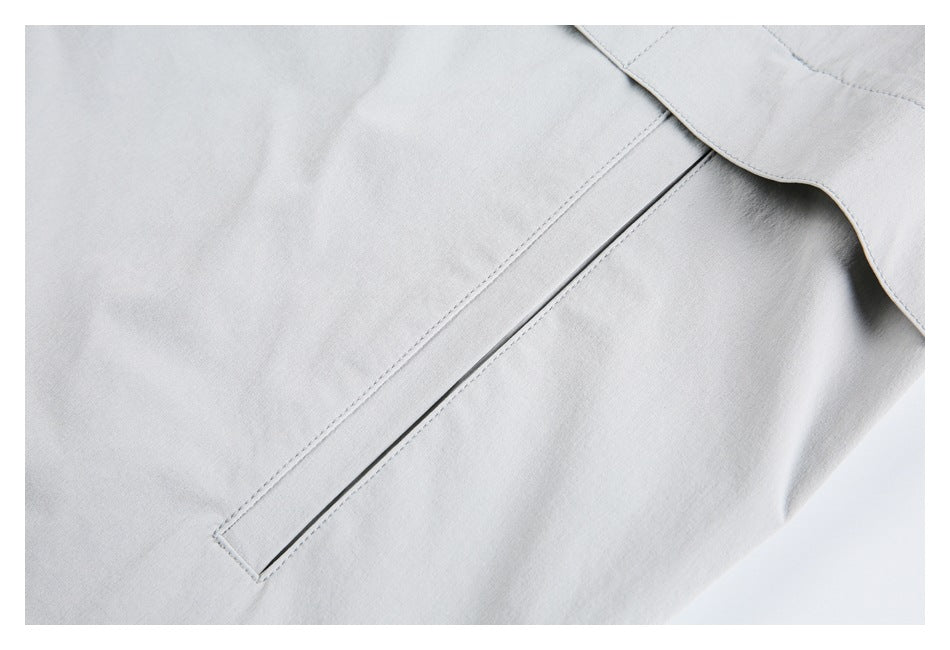 Close-up of a slim welt pocket on the light gray jacket.