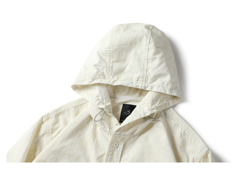Upper front of an off-white hooded button-up shirt, showing the hood, drawcords, and top button.