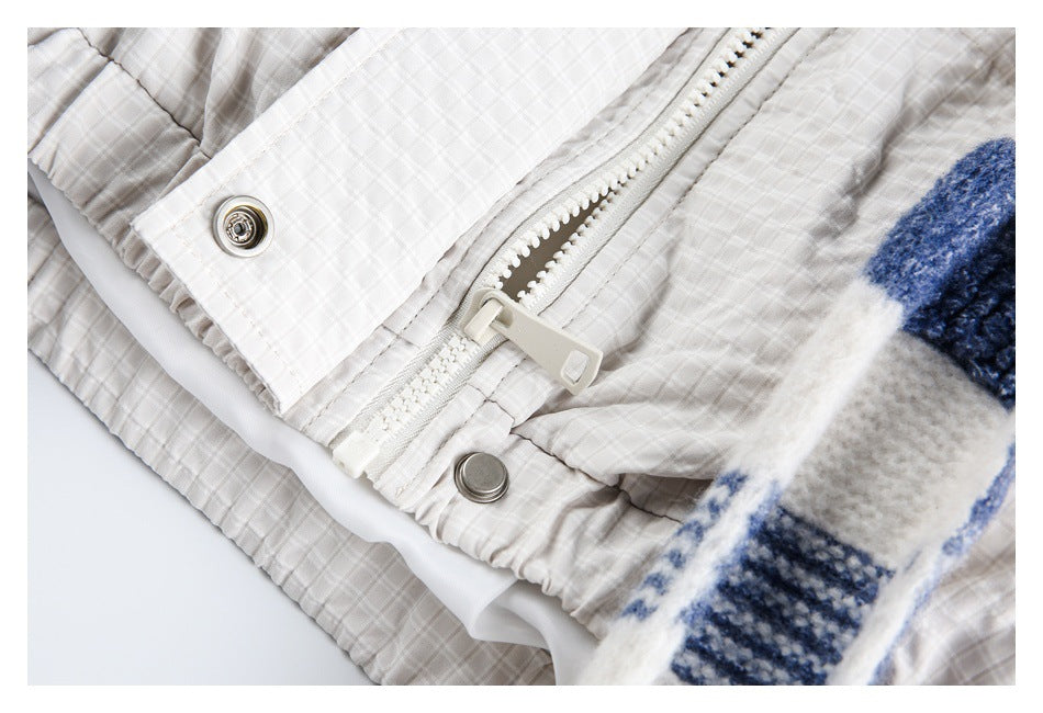 Close-up of a pale check garment with a white zipper, metal snaps, and fuzzy blue-and-white striped lining.