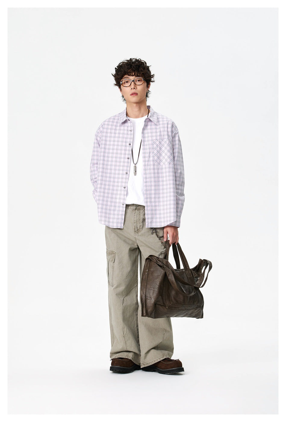 Full-length model wearing an oversized pale pink plaid shirt over a white tee and khaki cargo pants.