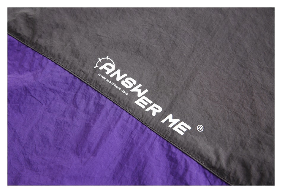 Close-up of charcoal and purple color-block fabric with white lettering printed on the garment.