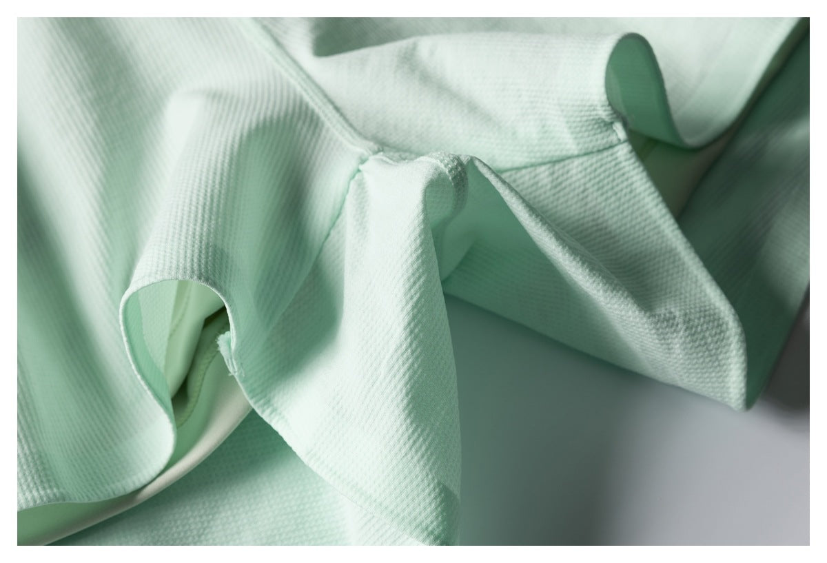 Close-up of pale mint garment construction, showing folded edges and stitched seams.