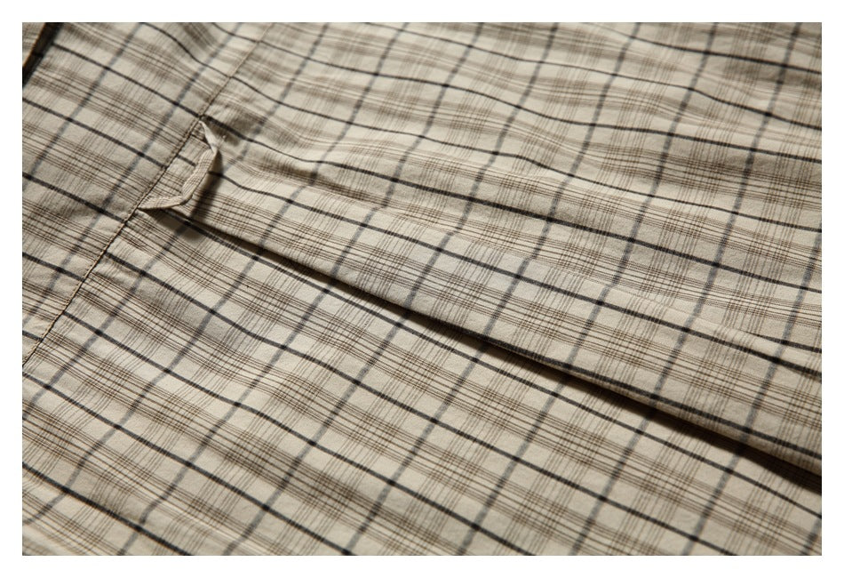 Close-up of beige and brown plaid garment fabric with a folded seam.