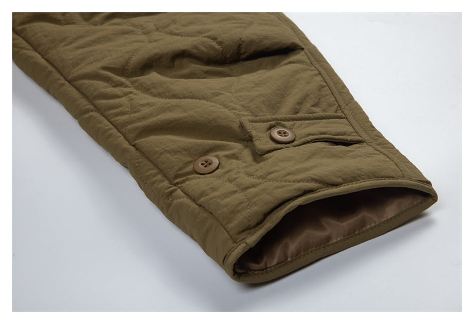 Close-up of an olive-brown quilted jacket sleeve cuff with two buttons and brown lining.