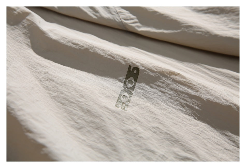 Close-up of a small dark graphic mark on the beige jacket fabric.