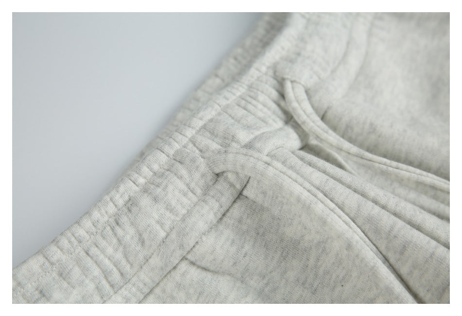 Close-up of the waistband, drawstring, and slanted pocket seam on light gray marl sweatpants.