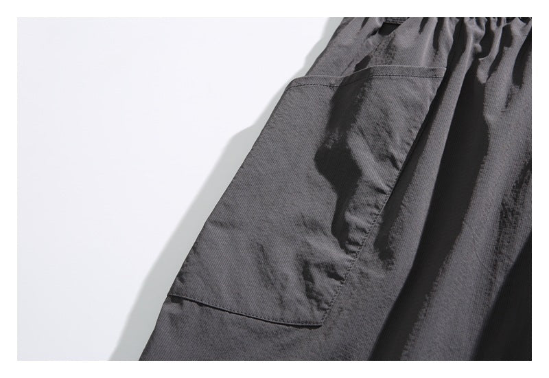Close-up of a dark gray garment showing a large stitched patch pocket and textured fabric.