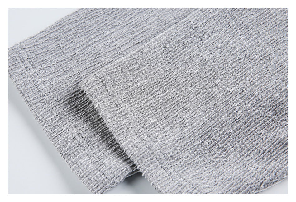 Close-up of a side slit and hem on the light gray textured shirt.