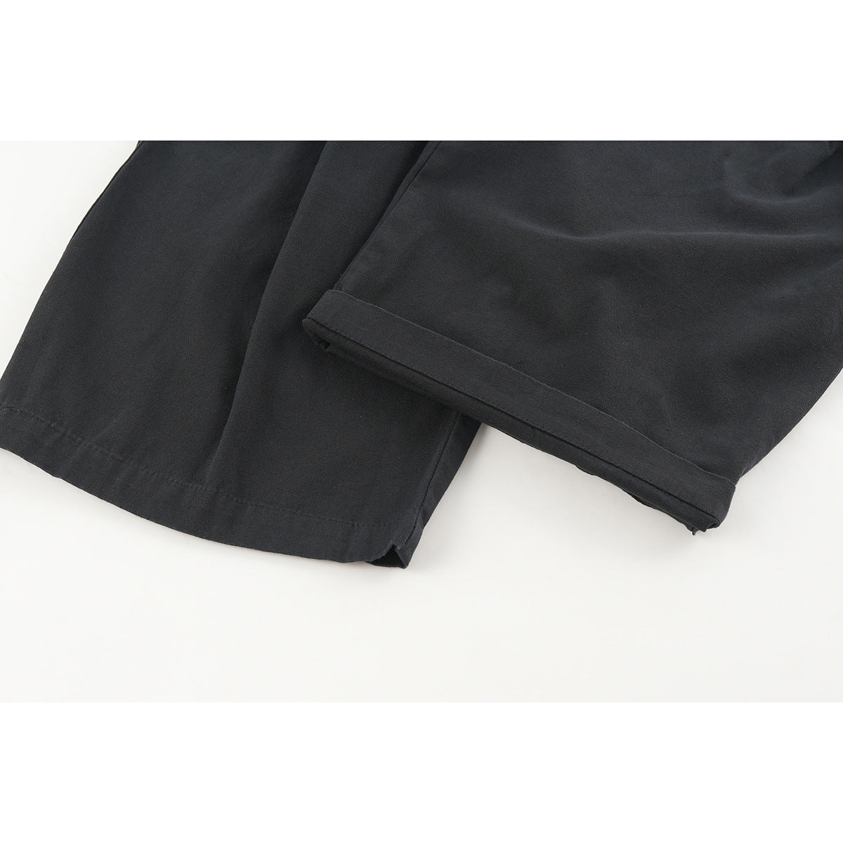 Close-up of the black pants' wide hems and stitched edges.