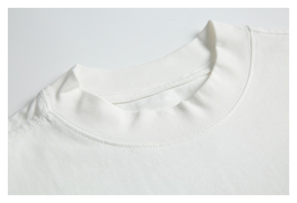 Close-up of the ribbed crew neckline and shoulder seam of a white T-shirt.