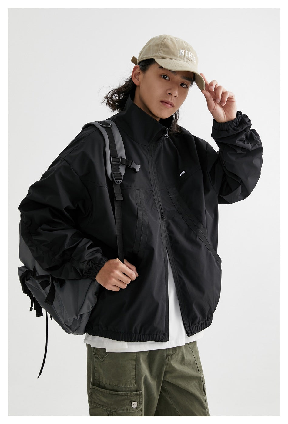Model wearing a black zip-front jacket with a stand collar, angled front pockets, and elastic cuffs.