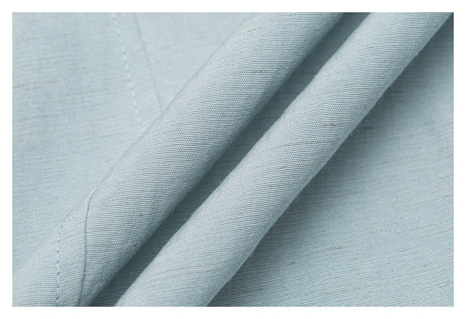 Close-up of a folded, stitched fabric edge on a pale blue garment.