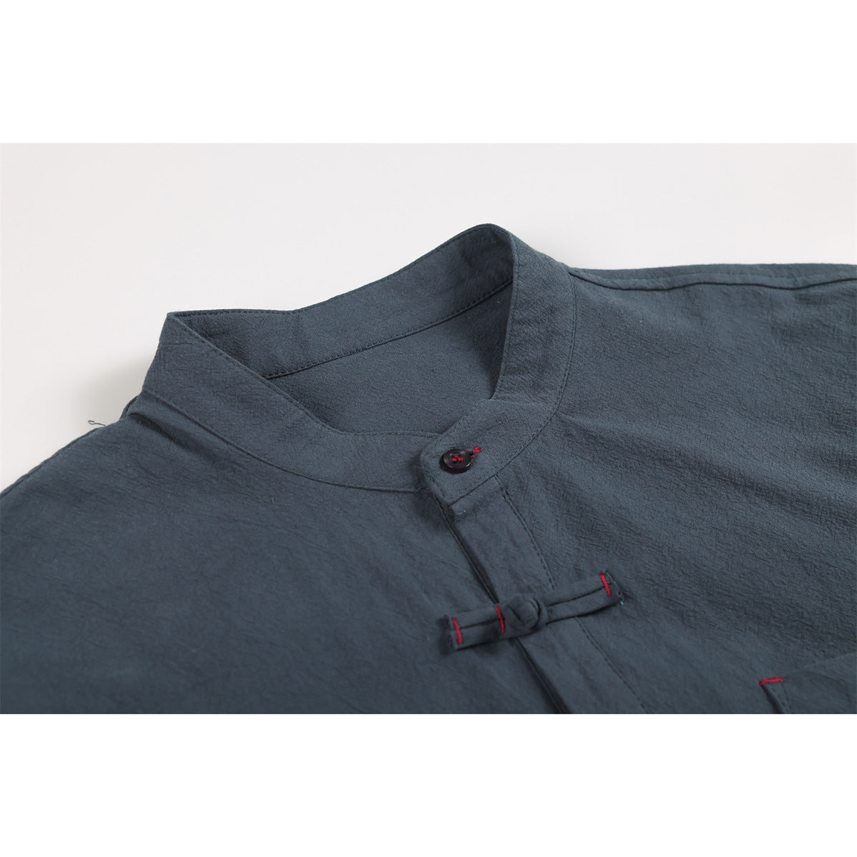 Close-up of a dark slate shirt's stand collar and frog closure with red stitching.