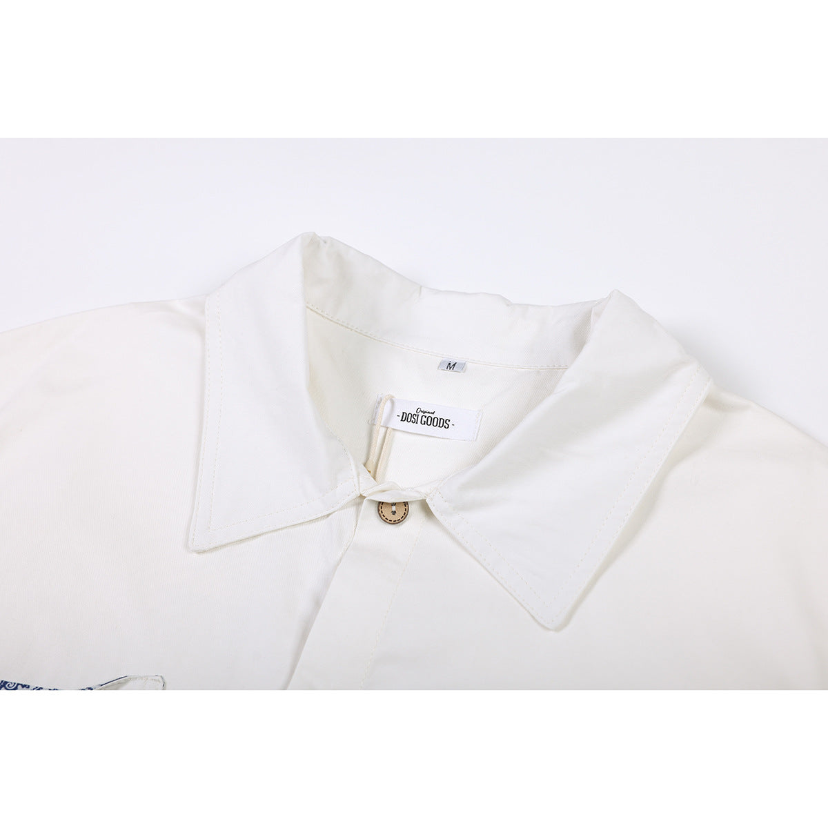 Close-up of an ivory shirt collar with a tan button and visible DOSI GOODS label.
