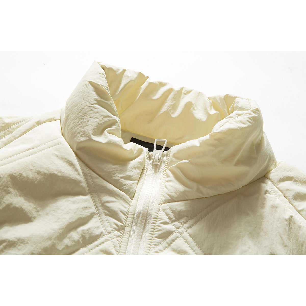 Close-up of an ivory quilted jacket's oversized stand collar and front zipper.