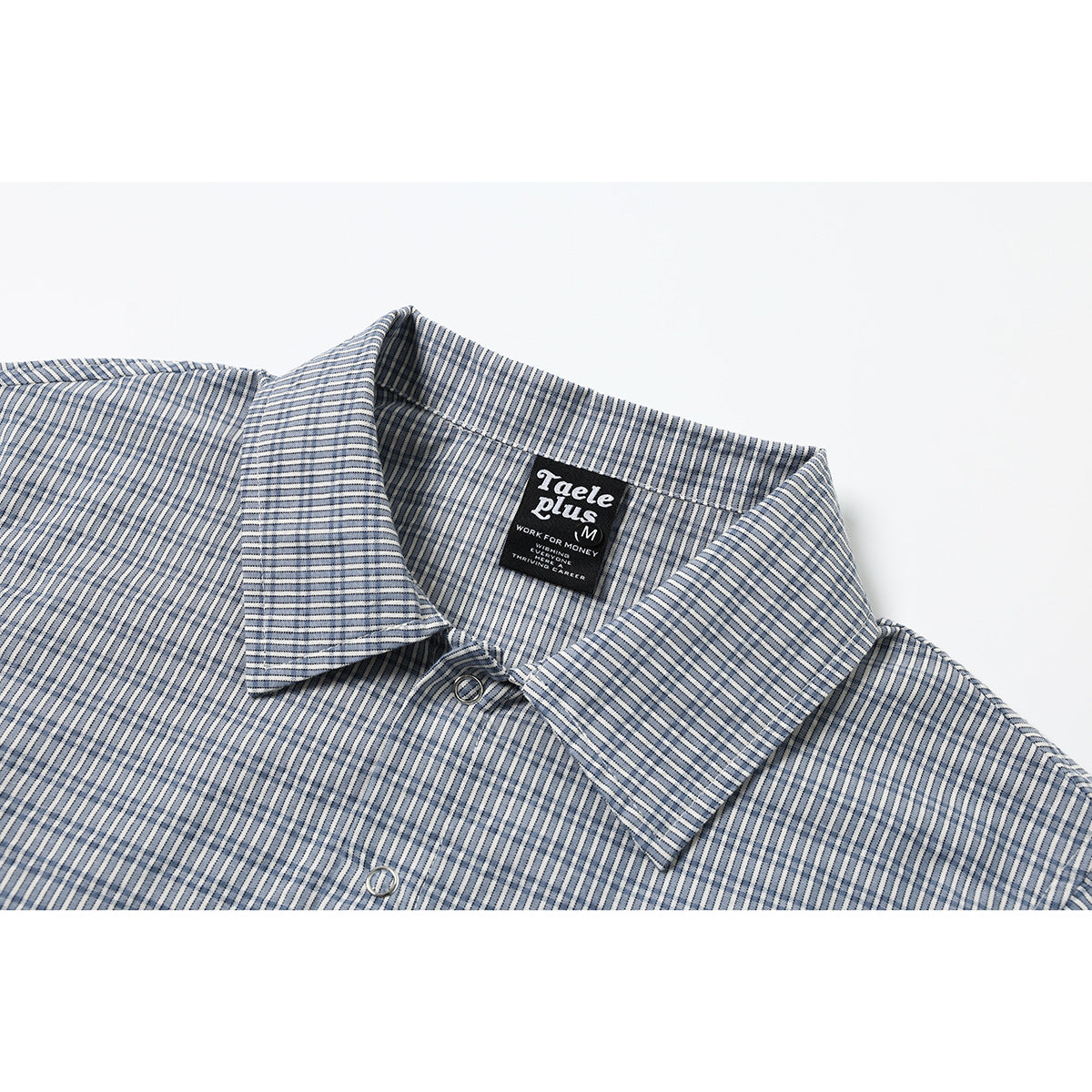 Close-up of a blue-and-white checked short-sleeve shirt collar, button, and sewn neck label.