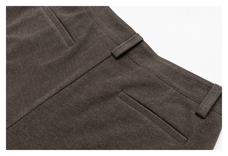 Close-up of dark brown trousers showing the waistband, belt loops, and a welt pocket.