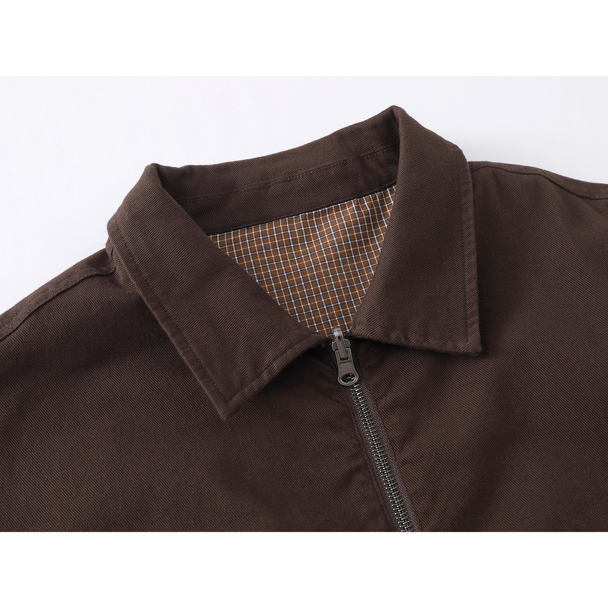 Close-up of a dark brown jacket collar, front zipper, and brown plaid lining.
