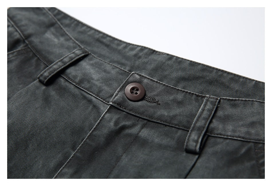 Close-up of charcoal pants showing the waistband, dark button, belt loops, and stitching.